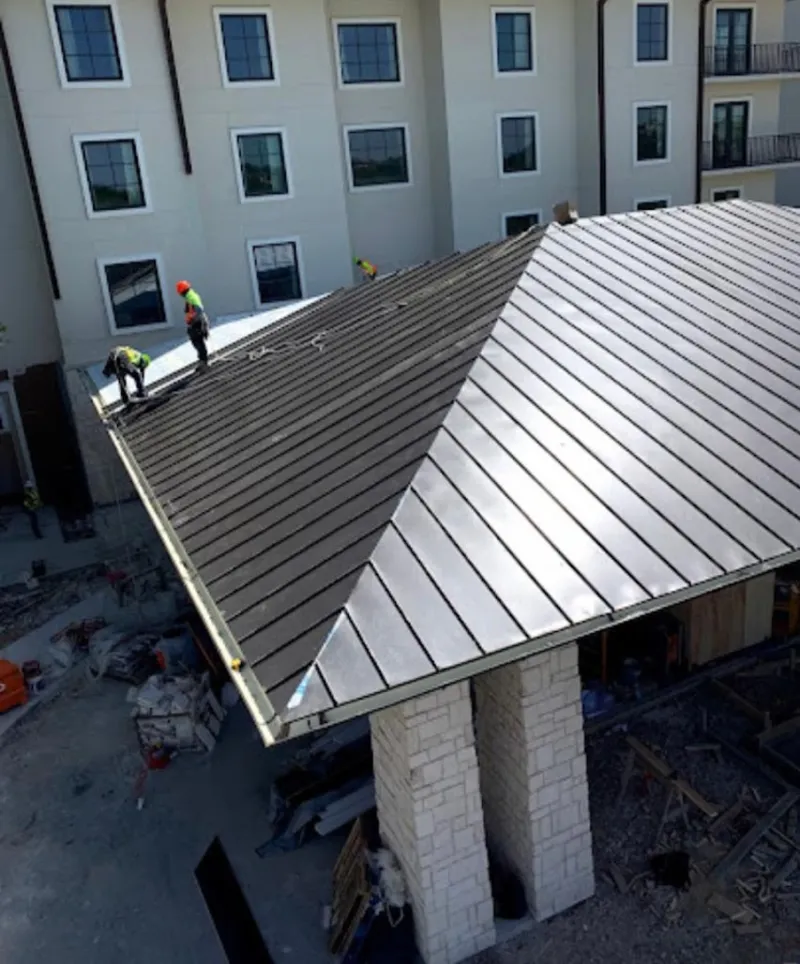 Crew installing standing seam metal roof panels on a commercial project in South Lebanon